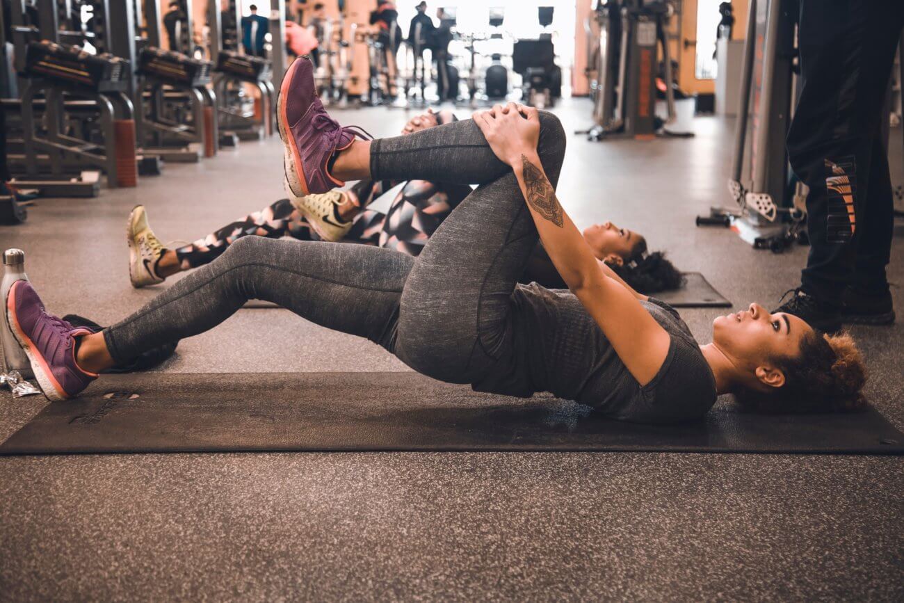 mujer, colocar, en, un, estera, estirar, ella, pierna, en, un, gimnasio